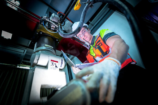 A robotics engineer uses a tablet to program a robot with a machine vision system, while her colleague calibrates the end-of-arm tooling on another unit in a system integration lab.
