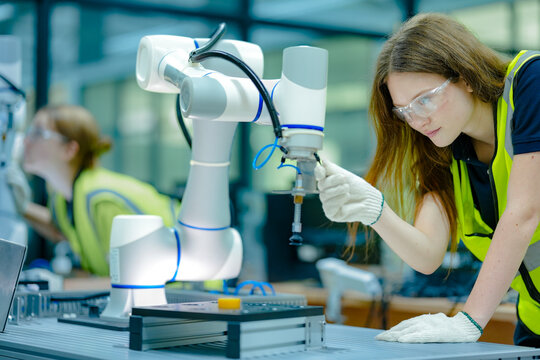 Two technicians program a collaborative robot cobot for a precise pick-and-place task, working safely alongside the machine to optimize its movements and end-effector grip.
