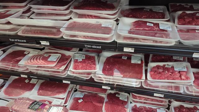 Aisle product showcase for meat in supermarket. Shopping in Supermarket. Many packaged raw red meat on supermarket shelves, assortment on showcase in butcher shop. Food, meats in supermarket, grocery.
