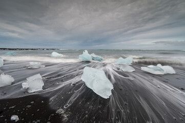 Diamond Beach in Iceland with blue icebergs melting on the black sand and ice glistening, beautiful arctic nature scenery, Icelandic South coast, Jokulsarlon. © aroxopt