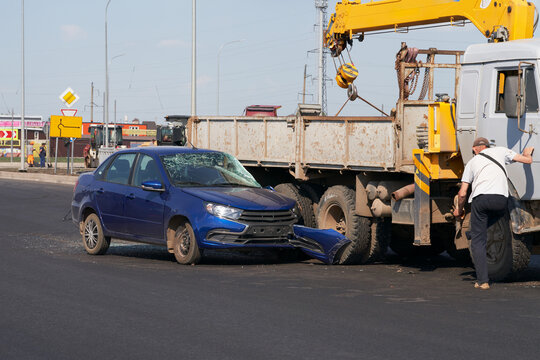A traffic accident. A car collided with a truck on the road. The car's left headlight, bumper, and windshield were damaged.