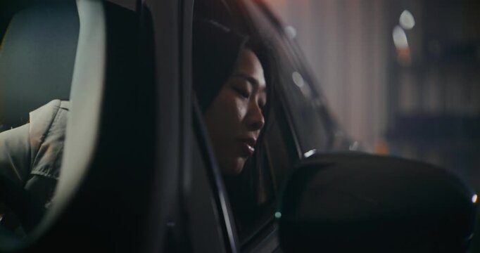 Asian Woman Drive Car Out of Garage. Girl Leans Out of Open Driver Side Window, Face Emotional Argument With Someone. Young Female Using Expressive Hand Gestures, Appears Frustrated and Defensive.