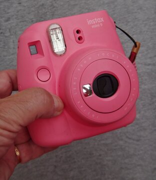 Hand holding pink Fujifilm Instax Mini 9 camera