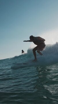 Stylish surfer. Young man in bright colorful shirt surfs the wave. Speed warp effect applied with frozen movement of the rider
