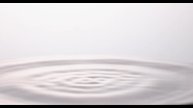 4K slow motion macro of transparent water droplet rising after impact, ripple waves on surface, clean drinking water and pure hydration concept, studio shot