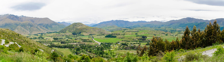 Fototapeta premium Arrow Junction Lookout Point in New Zealand: rolling green hills, valleys, and fields interspersed with trees. 