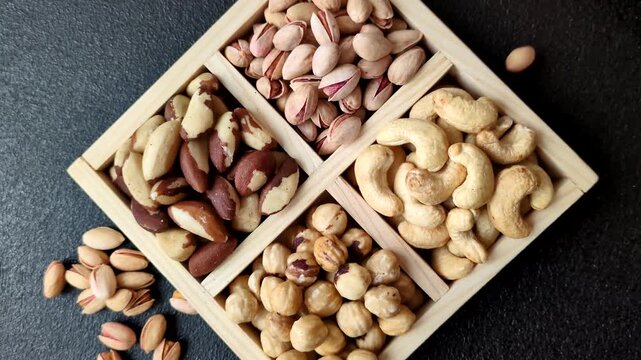 A box of cashews, hazelnuts, pistachios, and Brazil nuts as healthy food ingredients. A box of nuts as a backdrop for your design