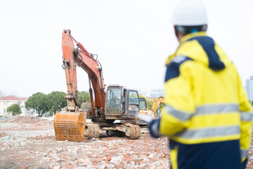 Construction worker in high-visibility uniform supervising orange excavator operation at demolition site © zhu difeng