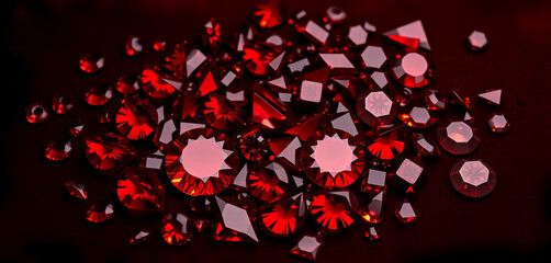 Small red gemstones of various shapes are placed together on a dark surface. They are used for crafting and decorating items in a workshop