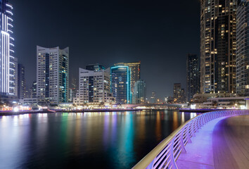 Fototapeta premium Deep neighborhood imprint skyline perspective wide canal framed by Dubai Marina residential towers and electric reflections at night for authentic metropolitan tourism and regional city branding.