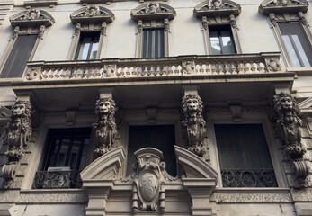 rnate historic building facade in Milan, Italy featuring sculpted lion corbels, decorative balcony and classical window details on elegant European architecture.