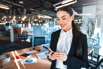 Fototapeta premium Confident Businesswoman Holding Smartphone in Modern Office