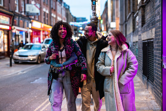 Diverse friends laughing walking city street evening carrying roller skates