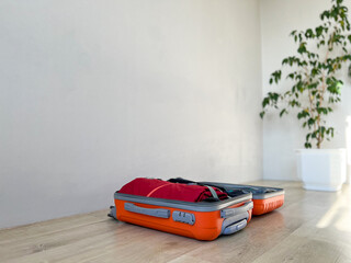 Orange suitcase packing clothes for travel departure