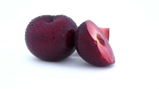 Close-up of a juicy, ripe plum, one half cut open revealing its vibrant red flesh. animation