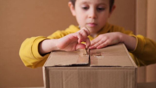 Child opening a cardboard box in 4K. Close-up b-roll of a young boy's hands opening the flaps of a delivery package, illustrating curiosity, unboxing, and the excitement of a new arrival