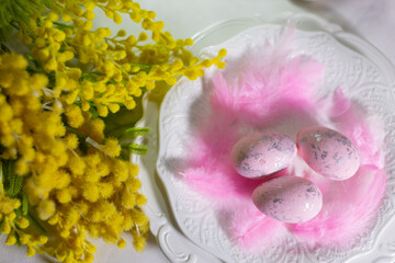 pink Easter eggs on a serving plate. Bouquet of yellow mimosa on the table, Easter holiday