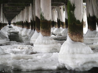 Dewniane słupy oblodzone u podstawy. Zima nad morzem. Molo w Sopocie. © EwaAF