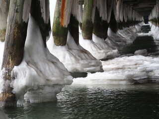 Dewniane słupy oblodzone u podstawy. Zima nad morzem. Molo w Sopocie. © EwaAF