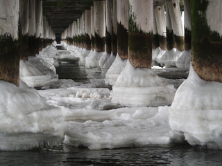 Dewniane słupy oblodzone u podstawy. Zima nad morzem. Molo w Sopocie. © EwaAF