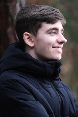 Male in black winter jacket. Smiling young guy. Winter forest	
