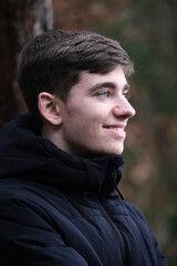 Male in black winter jacket. Smiling young guy. Winter forest	
