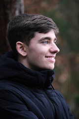 Male in black winter jacket. Smiling young guy. Winter forest	
