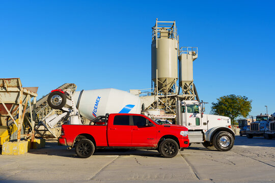 Perris, California - December 6, 2025: Red RAM Pickup Truck and Concrete Mixer at Industrial Facility in California