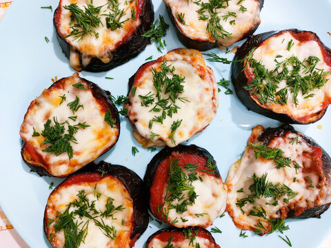 Roasted eggplant slices topped with tomato sauce, melted cheese, and fresh dil