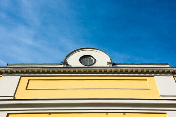 Classic building facade with circular window against blue sky.