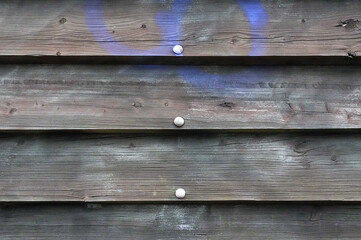 Fototapeta premium Wooden planks with holes and a blue spot on the wall
