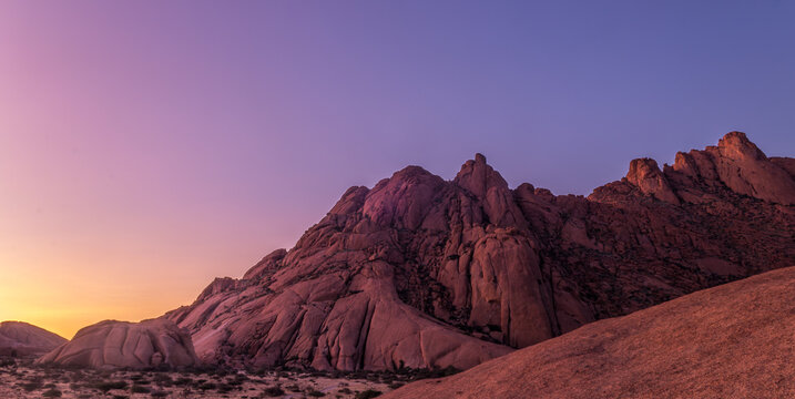 Namibia - Spitzkoppe - Panoramic view of rugged granite mountain range illuminated by soft evening light at sunset