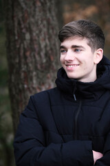 Male in black winter jacket. Smiling young guy. Winter forest	
