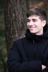 Male in black winter jacket. Smiling young guy. Winter forest	
