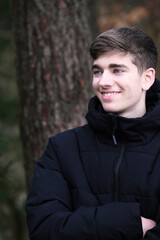 Male in black winter jacket. Smiling young guy. Winter forest	
