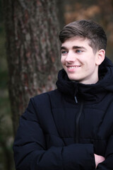 Male in black winter jacket. Smiling young guy. Winter forest	
