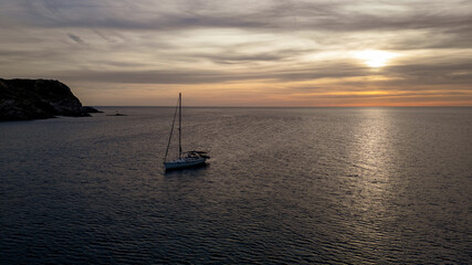 Fototapeta premium Sailboat at sunset in Argentiera, Sardinia: Peace and golden reflections