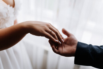 Bride and groom holding hands with wedding ring, romantic marriage moment close up