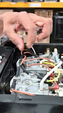 Coffee machine with grinder being checked and repaired by a technician repairing electrical appliances with a screwdriver, performing maintenance and wiring on the machine.