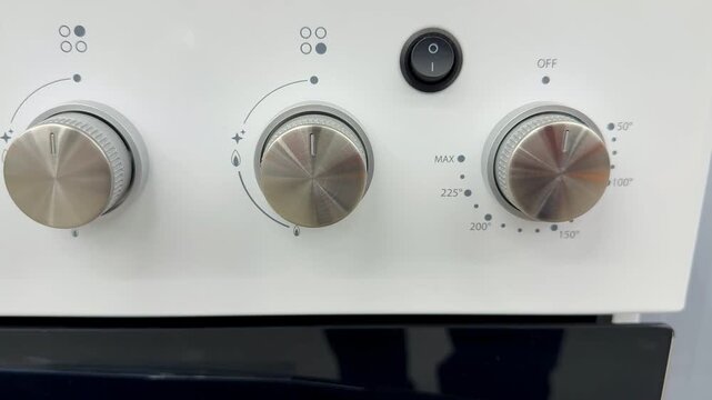 White electric stove with glass cooktop on showroom shelf, visible control knobs and mode dials, crisp enamel body, reflective.