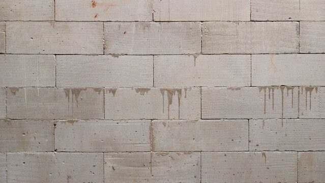Grey aerated concrete block wall texture with cement drips. grunge wallpaper.