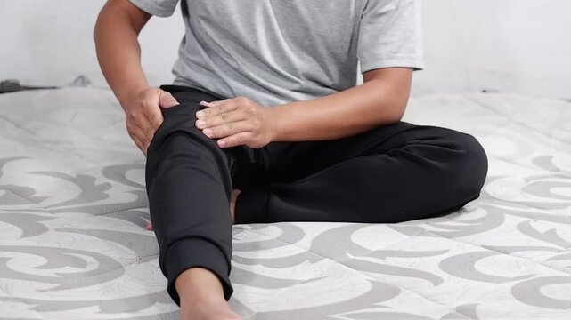 A young man massages his knee due to knee pain and muscle aches caused by Runner's Knee or Patellofemoral Pain Syndrome, osteoarthritis, arthritis, rheumatism, and Patellar Tendinitis. Medical concept