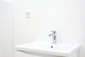 Fototapeta premium Modern bathroom sink with chrome faucet and white tiled wall