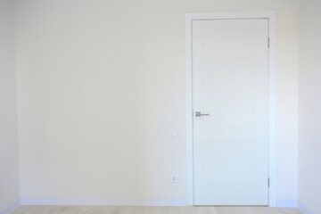 Empty room interior with white walls and closed door on the right side