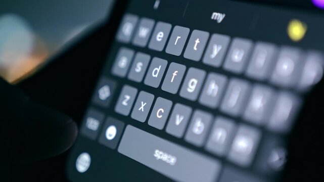 Extreme close-up of person typing message on smartphone keyboard at night. Online texting, digital communication, social media chat concept, screen glow in dark, 4K video.