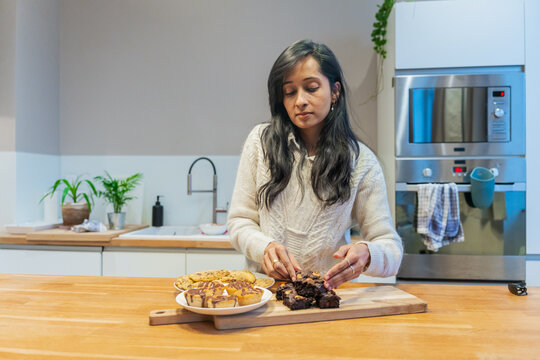 Woman Organizing Brownies And Pastries In Kitchen