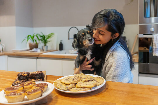 Woman Hugging Dog In Kitchen With Treats