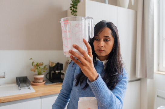 Indian Woman Measuring Ingredients In Jug

