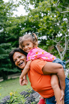 grandmother 
smiling and playing with her granddaughter on her back