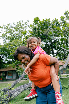 grandmother 
smiling and playing with her granddaughter on her back